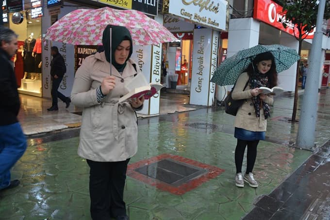 Kitap okumaya teşvik için yağmur altında kitap okudular