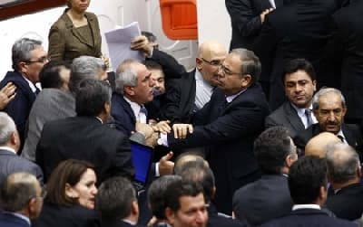 <p><font face="arial,helvetica,sans-serif" size="2">Erdoğan, internet sitelerinde nelerin dolaştığını, ne t&uuml;r belden aşağı vurmaların olduğunu &ccedil;ok iyi bildiklerini belirterek, partisinde, bu şekilde bir yakıştırmayı yapanın barınamayacağını kaydetti.</font></p><p><font face="arial,helvetica,sans-serif" size="2">MHP Grup Başkanvekili Oktay Vural'ın elindeki CD'yi g&ouml;stermesi ve MHP'lilerin laf atması &uuml;zerine Erdoğan, ''<font color="#333399">Susmayı &ouml;ğren, &ouml;nce susmayı &ouml;ğren, dinlemeyi &ouml;ğren. Kaldı ki benimle ilgili bu t&uuml;r yakıştırmayı yapan siz, ayrıca eşime laf atamazsınız. Bu edepsizliktir, izansızlıktır, ahlaksızlıktır. Sen baş&ouml;rt&uuml;l&uuml;ler &uuml;zerinden oy toplamak isteyeceksin; eşimin baş&ouml;rt&uuml;s&uuml; sebebiyle... Eşimi baş&ouml;rt&uuml;s&uuml; sebebiyle GATA'ya sokmayanları m&uuml;dafaa edecek kadar da izansızsın'' </font>diye konuştu.</font></p><p><font face="arial,helvetica,sans-serif" size="2"><strong>Ve Kavga...<br /></strong><br />MHP milletvekillerinin Erdoğan'a laf atarak ayağa kalkmaları &uuml;zerine, AK Parti milletvekilleri, MHP sıralarına doğru y&uuml;r&uuml;d&uuml;. TBMM Başkanvekili G&uuml;ldal Mumcu,gerilimin artması &uuml;zerine birleşime ara verdi.</font></p><p><font face="arial,helvetica,sans-serif" size="2"><strong>Gensoru &Ouml;nergesi Reddedildi</strong></font></p><p><font face="arial,helvetica,sans-serif" size="2">TBMM Genel Kurulunda, MHP'nin, &Ccedil;alışma ve Sosyal G&uuml;venlik Bakanı &Ouml;mer Din&ccedil;er hakkında verdiği gensoru &ouml;nergesinin g&uuml;ndeme alınması kabul edilmedi.</font></p><p><font face="arial,helvetica,sans-serif" size="2">Verilen arada milletvekillerinin s&ouml;zl&uuml; tartışması, yumruklaşmaya d&ouml;n&uuml;şt&uuml;. Başbakan Recep Tayyip Erdoğan, kavga sırasında Genel Kuruldan ayrılırken, MHP Genel Başkanı Devlet Bah&ccedil;eli, salonda oturmaya devam etti.</font></p><p><font face="arial,helvetica,sans-serif" size="2">Bakanlar Kurulu &uuml;yeleri, grup başkanvekilleri ve idare amirleri, kavgayı &ouml;nlemek i&ccedil;in milletvekillerinin arasına girdi. TBMM İdare Amiri Orhan Erdem'in, kavgayı ayırmaya &ccedil;alışırken yumruk yediği g&ouml;r&uuml;ld&uuml;. Erdem'i, iki milletvekili kolundan tutarak, Genel Kurul Salonundan &ccedil;ıkardı. </font><font face="arial,helvetica,sans-serif" size="2">Sinirlenerek, MHP Grup Başkanvekili Mehmet Şandır'ın &uuml;zerine y&uuml;r&uuml;mek isteyen Sağlık Bakanı Recep Akdağ'ı, BDP Şırnak Milletvekili Hasip Kaplan engelledi.</font></p><p><font face="arial,helvetica,sans-serif" size="2">Kavga sırasında AK Parti İstanbul Milletvekili Halide İncekara da Başkanlık Divanındaki tokmağa vurarak, milletvekillerini yatıştırmak istedi. </font><font face="arial,helvetica,sans-serif" size="2">Yumruklaşmaya varan kavgada, AK Parti Grup Başkanvekili Ayşe Nur Bah&ccedil;ekapılı ve MHP İstanbul Milletvekili Durmuşali Torlak'ın g&ouml;zl&uuml;ğ&uuml; kırıldı.</font></p><p><font face="arial,helvetica,sans-serif" size="2">Aranın ardından AK Parti Tokat Milletvekili Zeyid Aslan, birleşimi y&ouml;neten TBMM Başkanvekili G&uuml;ldal Mumcu'ya, <font color="#333399">''TBMM İdare Amiri Orhan Erdem'e yapılan saldırıyı kınamıyor musunuz?'' diye sordu. </font></font><font face="arial,helvetica,sans-serif" size="2"><font color="#333399">CHP milletvekillerinin, ''Meclis Başkanlığına yapılan saldırıyı kınamıyor musunuz''</font> karşılığını vermesi &uuml;zerine Aslan, <font color="#333399">''Siz kınamıyorsanız, ben kınıyorum''</font> dedi. AK Parti'li milletvekilleri araya girerek, Aslan'ı dışarıya &ccedil;ıkardı.</font></p><p><font face="arial,helvetica,sans-serif" size="2">Mumcu, Genel Kurulda yaşananları, hi&ccedil;bir milletvekilinin kendine yakıştıramayacağını ifade ederek, yaşananlardan duyduğu &uuml;z&uuml;nt&uuml;y&uuml; dile getirdi.</font></p><p><font face="arial,helvetica,sans-serif" size="2"><strong>&Ouml;ncesi de Gergindi</strong><br /><br />Durmuş'un &quot;<font color="#333399">peygamber</font>&quot; demesi tartışmayı yumruklaşmaya d&ouml;n&uuml;şt&uuml;rd&uuml;. Ancak gensoru g&ouml;r&uuml;şmelerindeki gerginlik bununla sınırlı değil. CHP İstanbul Milletvekili &Ccedil;etin Soysal konuşmasında TEKEL iş&ccedil;ilerinin durumunu hatırlattı, daha sonra &quot;<font color="#333399">&Ouml;nce m&uuml;cahittiniz, m&uuml;şahit oldunuz, m&uuml;teahhit oldunuz, daha sonra her şeye m&uuml;sait oldunuz. Yetim hakkından bahsediyorsunuz, o kasanın kimlere &ccedil;alıştığını, kediye ciğer teslim edildiğini g&ouml;r&uuml;yoruz</font>.&quot; ifadelerini kullandı.</font></p><p><font face="arial,helvetica,sans-serif" size="2">AK Parti Grup Başkanvekili Ayşe Nur Bah&ccedil;ekapılı, sataşma olduğu gerek&ccedil;esiyle s&ouml;z aldı. Bah&ccedil;ekapılı,''<font color="#333399">Kişilerin &ouml;zel hayatına m&uuml;dahale insan haklarına aykırıdır, ayrıca ayıptır. Hukukta eleştiri ile hakaret arasında bazı kriterler vardır. Eleştirirken kullandığınız dil ile s&ouml;ylediklerinizin i&ccedil;eriğinin birbiriyle &ouml;rt&uuml;şmesi, bir denge kurulması gerekir. Burada, paparazzi programlarına konu olmak i&ccedil;in bulunmuyoruz. Facebook'ta en &ccedil;ok tıklanan oyuncak da değiliz. &Ouml;nce &ccedil;alışın sonra konuşun'' </font>dedi.<br /></font><font face="arial,helvetica,sans-serif" size="2"><br />Soysal'ın ''<font color="#333399">Adres belli, adres Başbakan'</font>' demesi, AK Parti'li milletvekillerinin tepkisine yol a&ccedil;tı. Sıra kapaklarına vuran AK Parti'li milletvekilleri, <font color="#333399">''Terbiyesiz, ahlaksız, sarhoş, kafayı &ccedil;ekip geliyorsun...</font>'' diye tepki g&ouml;sterdi. <font color="#333399">''Ahlaksız sensin, terbiyesiz sensin. Bizi yıldıramazsınız''</font> diyen Soysal, <font color="#333399">''Burada siyaset seviye dersi vermek, en son size d&uuml;şer. Siyasetin kıblesinin insan olduğunu bilenleriz. Siz, &ccedil;ivi &ccedil;aktınız doğru ama bu &ccedil;ivileri insan etine &ccedil;akıyor, insanları acıtıyorsunuz</font>'' diye konuştu.</font></p><p><font face="arial,helvetica,sans-serif" size="2">TBMM Başkanvekili G&uuml;ldal Mumcu, Sosyal'ın konuşma s&uuml;resinin bitmesinin ardından birleşime ara verdi. AK Parti milletvekilleriyle birbirlerine karşılıklı laf atan Soysal'ı, CHP'li milletvekilleri k&uuml;rs&uuml;den indirdi. soysal'ın, AK Parti milletvekillerinin &uuml;zerine y&uuml;r&uuml;mesini, idare amirleri, arkadaşları ve Grup Başkanvekilleri &ouml;nledi.</font></p>