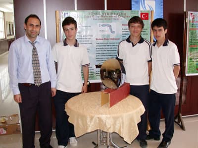 <p><font face="verdana,geneva" size="2">Proje takımında yer alan &ouml;ğrenciler Yusuf Esen, Ali Altıntaş, Mustafa Kılı&ccedil;bay ve Enes Kılı&ccedil; ışık almayan t&uuml;nellerin masraflı bir şekilde &uuml;retilen elektrik enerjisi yerine g&uuml;neş enerjisiyle aydınlatılması i&ccedil;in &ccedil;&ouml;z&uuml;m yolu aradı. 3 ay s&uuml;ren bir araştırma sonucu t&uuml;nellerinde g&uuml;neş enerjisiyle aydınlatabilecek proje hazırlandı. </font></p><p><font size="2"><font face="verdana,geneva"><font color="#cc0000"><strong>&quot;T&uuml;nel Aydınlatma&quot;</strong></font> adı verilen projeyle; t&uuml;nel &uuml;zerine konan ve g&uuml;neşin hareketini takip eden &ccedil;ukur ayna ile g&uuml;neş ışınları toplanıyor. Başka bir ayna ile toplanan bu ışınlar, b&uuml;y&uuml;k aynanın tepe noktasına yerleştirilen ve i&ccedil;erisi y&uuml;zde 95 oranında yansıtıcı olan fiber optik kablolar yardımı ile ile t&uuml;nel i&ccedil;erisine taşınarak t&uuml;nelin g&uuml;nd&uuml;z saatlerinde g&uuml;neş ışınları ile aydınlatılmasını sağlıyor. </font></font></p><p><font face="verdana,geneva" size="2">Proje ile 45-50 santimetre &ccedil;apında bir &ccedil;ukur ayna ile toplanan g&uuml;neş ışınlarının 400 watt'lık ampul&uuml;n aydınlatmasına eşdeğer bir aydınlatma sağlıyor. </font></p><p><font face="verdana,geneva" size="2"></font></p><font face="verdana,geneva" size="2">Işık Eğitim Kurumları Genel M&uuml;d&uuml;r&uuml; Yaşar Narı, okulda proje takımları oluşturduklarını, &ouml;ğrencilerin k&uuml;resel ısınma konusunda &ccedil;ok farklı projeler hazırladıklarını ve bunları kamuoyu ile paylaşacaklarını kaydediyor. </font>